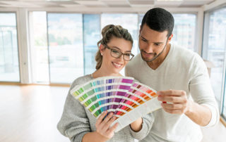 Happy Couple Painting Their House And Choosing A Color From A Palette